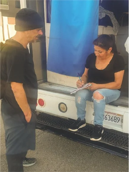 a man wearing a beanie and woman sitting on a vehicle while writing